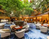 Luksusowy hol hotelowy z bujną roślinnością, wygodnymi fotelami i ozdobnym dywanem. Idealne miejsce na relaks w sieci luksusowych hoteli.