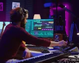 Un artista di musica elettronica lavora nel suo studio, mixando suoni con attrezzature professionali e un software di produzione musicale.