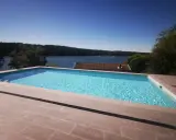 En lyxig pool med klarblått vatten och en fantastisk utsikt över en sjö. En dröm för många, men vad är bygga pool kostnad?