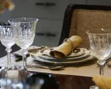 Verre à pied taillé, assiettes décorées, serviette en tissu joliment pliée : une table dressée pour le service à la française.