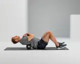 Mann macht Foam Rolling auf einer Matte, um seinen Rücken zu entspannen.