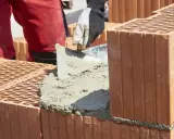 Budowanie muru z pustaków ceramicznych, nakładanie zaprawy. Właśnie tak jak zrobic cement do budowy.