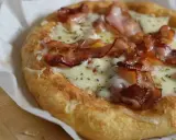 Pyszna pizza z mozzarellą i chrupiącym boczkiem, posypana ziołami. Idealna na szybki lunch.