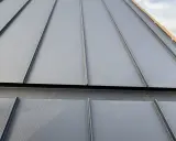 Szara blacha na rąbek stojący z widocznymi wadami montażu, np. niedokładne połączenia.
