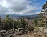 Widok na Karpacz zalesionymi wzgórzami i górami w tle, z kamienistym pierwszym planem.