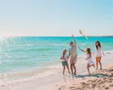 Rodzina puszcza latawiec na piaszczystej plaży. Piękne kąpieliska nad Bałtykiem zachęcają do zabawy.