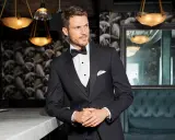 A man in a sharp tuxedo, perfect for any black tie event or formal occasion. He embodies the classic tuxedo dress code with a crisp white shirt and bow tie.