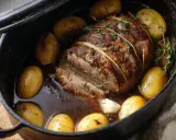 Un rôti de quasi de veau, lié à la ficelle, mijote dans un jus savoureux avec des pommes de terre et de l'ail.
