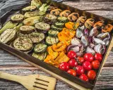 Buntes Gemüse wie Auberginen, Zucchini, Paprika, Zwiebeln und Tomaten auf einem Blech für ein köstliches vegetarisches Grillen.