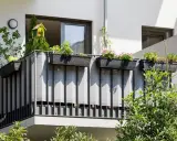 Balcone condominio con fioriere e telo grigio per creare idee privacy. Un nido per uccelli decora la vegetazione.