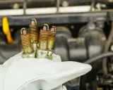 Zużyte świece zapłonowe w dłoni mechanika. Zastanawiasz się, ile kosztuje wymiana świec zapłonowych?