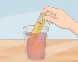 Une main tient un testeur de pH dans un verre d'eau. Le testeur affiche 3.24, indiquant que l'eau n'est pas à un pH neutre.