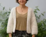 Mujer sonriente luce una chaqueta dos agujas tejida a mano, ideal para aprender paso a paso.