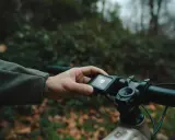 Main d'un cycliste ajustant l'écran d'un vtt electrique debridable en pleine nature.
