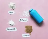 Blauer Behälter mit Babypuder, daneben Häufchen von Mehl, Speisestärke und Heilerde. Babypuder als trockenshampoo für schnelle Hilfe.