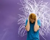 Junge mit roten Haaren hält sich die Ohren zu, vor chaotischer Kreidezeichnung. Ein Bild für die Herausforderungen von Kindern mit ADHS und Distanzlosigkeit.