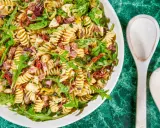 Pyszna sałatka z makaronem fusilli, rukolą, suszonymi pomidorami, oliwkami i kawałkami salami. Idealna na letnie dni.