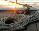 Coup de soleil sur un bateau, une corde épaisse est prête à faire un noeud de marin.