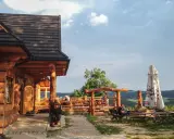 Drewniana bacówka Jamna z tarasem, gdzie goście jedzą, a obok stoi parasol. Menu bacówki Jamna kusi widokiem.