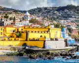 Gelbe Festung in Funchal, Madeira, mit Häusern, die sich den Hang hinaufziehen.