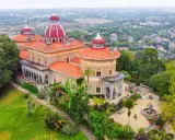 Der Monserrate Palast thront auf einem Hügel, umgeben von üppiger Vegetation und einer malerischen Stadt. Seine roten Dächer und Türmchen sind ein Blickfang.