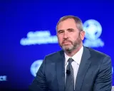 Brad Garlinghouse, CEO Ripple, w niebieskim garniturze, z brodą, na tle niebieskiej sceny z logo Global Conference.
