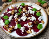 Ein Teller mit traditionellem Rote Bete Salat, garniert mit Feta, Walnüssen und Basilikum.