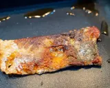 Ein Stück Lachs braten in der Pfanne, die Haut ist knusprig und goldbraun, das Fleisch saftig.