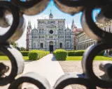 La Certosa di Pavia, un capolavoro rinascimentale, vista attraverso un cancello decorato. Un percorso conduce alla maestosa facciata.