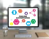 Komputer z hasłem "ONLINE ADVERTISING" i ikonami symbolizującymi różne formy reklamy online. Ciekawa reklama!