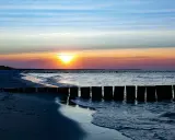 Zachód słońca nad Bałtykiem, falochrony i plaża w Sarbinowie. Piękne atrakcje Sarbinowo.