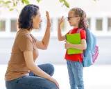 Madre y hija se dan un choque de manos, un momento de crianza positiva antes de ir a la escuela.