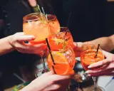 Hände stoßen mit Aperol Spritz an. So einfach wie man ihn macht, so erfrischend ist er!