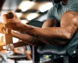 Ein Mann trainiert seinen Bizeps-Muskel an einem Gerät im Fitnessstudio. Die Adern treten deutlich hervor.