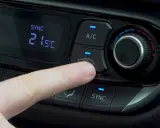 Dedo presionando el botón recirculacion aire del climatizador del coche.