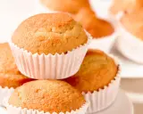 Ein Stapel goldbrauner, veganer Muffins in weißen Papierförmchen. Sie sehen köstlich und frisch gebacken aus.
