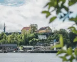 Widok na wybrzeże w Kristiansand, Norwegia. Żółte budynki na wzgórzu, czerwony klub kajakowy i wieża telekomunikacyjna.