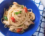 Un plat de pâtes aux crevettes, tomates cerises et basilic, servi dans un bol bleu vif. Un délice !