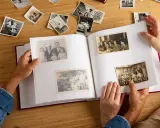 Manos hojeando un álbum de fotos antiguas, reviviendo recuerdos. Quizás buscando frases 50 aniversario para acompañar estas imágenes.