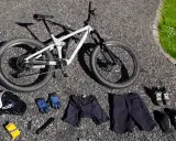 Fullt utrustad för en dag på stigarna: en grå heldämpad cykel, hjälm, handskar, shorts, skor och skydd. Allt för din mtb utrustning.