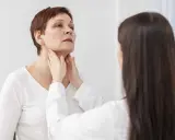 Medico esamina il collo di una paziente, possibile indicazione per una scintigrafia tiroidea.
