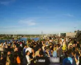 Folk samlas på en takbar med utsikt över vatten och stad. Många skrattar och minglar, en perfekt plats för gondolen recensioner.