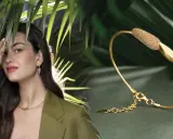 Modella con gioielli Pesavento, tra cui una collana, orecchini e anelli, su sfondo verde con foglie tropicali.