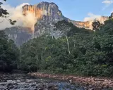Ein Fluss schlängelt sich durch üppigen Dschungel zum Fuß des Salto Ángel, dem höchsten Wasserfall der Welt, der von Wolken umhüllt ist.
