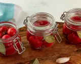 Słoiki z pysznymi, domowymi kiszonymi pomidorami, doprawione liściem laurowym i pieprzem. Idealne na zimę!