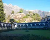 Un porticato ad archi domina un giardino curato, con montagne imponenti sullo sfondo. Un luogo ideale per scoprire cosa vedere a Chiavenna.