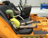 Maniquíes en un asiento de coche de prueba, preparándose para un test de seguridad según la normativa ECE R44/04.