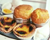 Pyszne portugalskie ciastka, w tym dwa kremowe pastel de nata i dwa muffinki, kuszą apetycznym wyglądem.