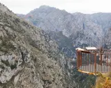 Mirador en la ruta del desfiladero de la Hermida, con imponentes montañas y un balcón de metal oxidado.