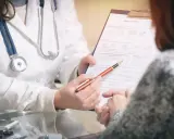 Lekarz omawia z pacjentem formularz medyczny, wyjaśniając, czy grupa inwalidzka ma wpływ na wysokość emerytury.